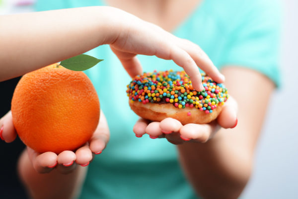 Child obesity concept with little girl hand choosing a sweet and
